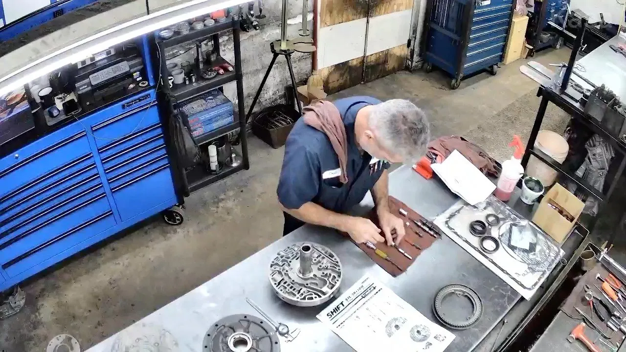 Overhead view of a teardown bench with valve body and transmission parts laid out for inspection